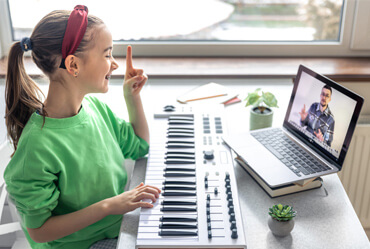 Niña en clases de piano virtual con profesor en Lima